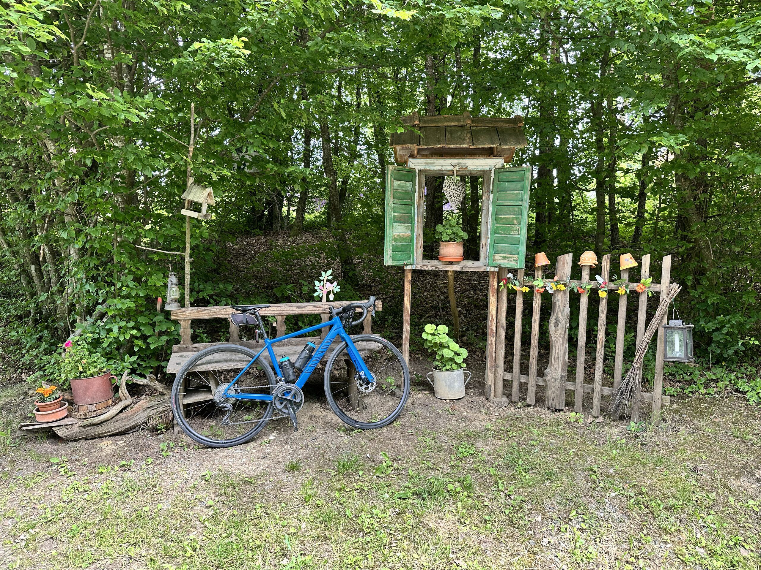A road bike leaning against a decorated wooden bench and fence in the Őrség